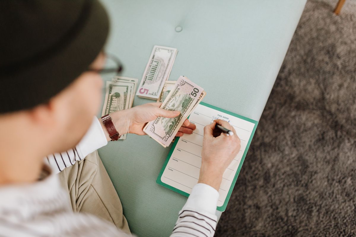 Person counting cash beside a budget planner