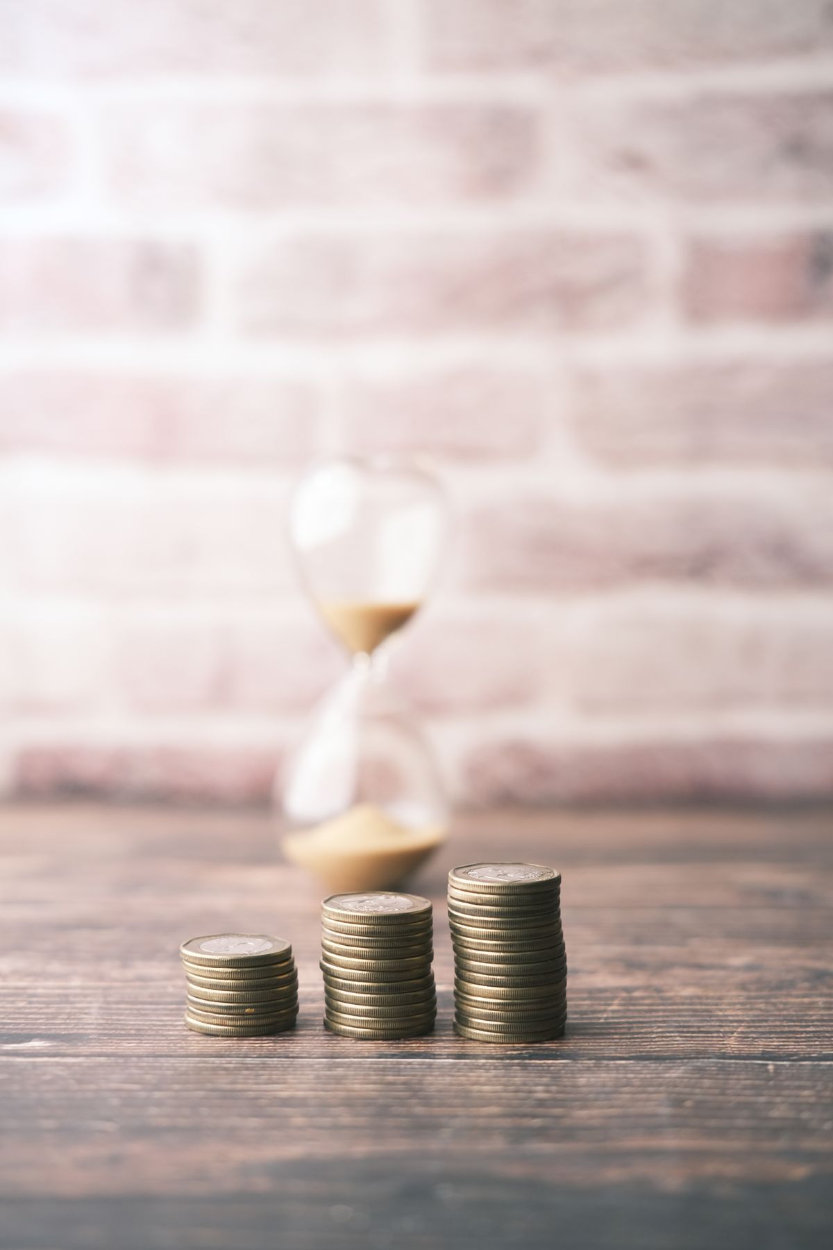 Stacks of coins beside an hourglass