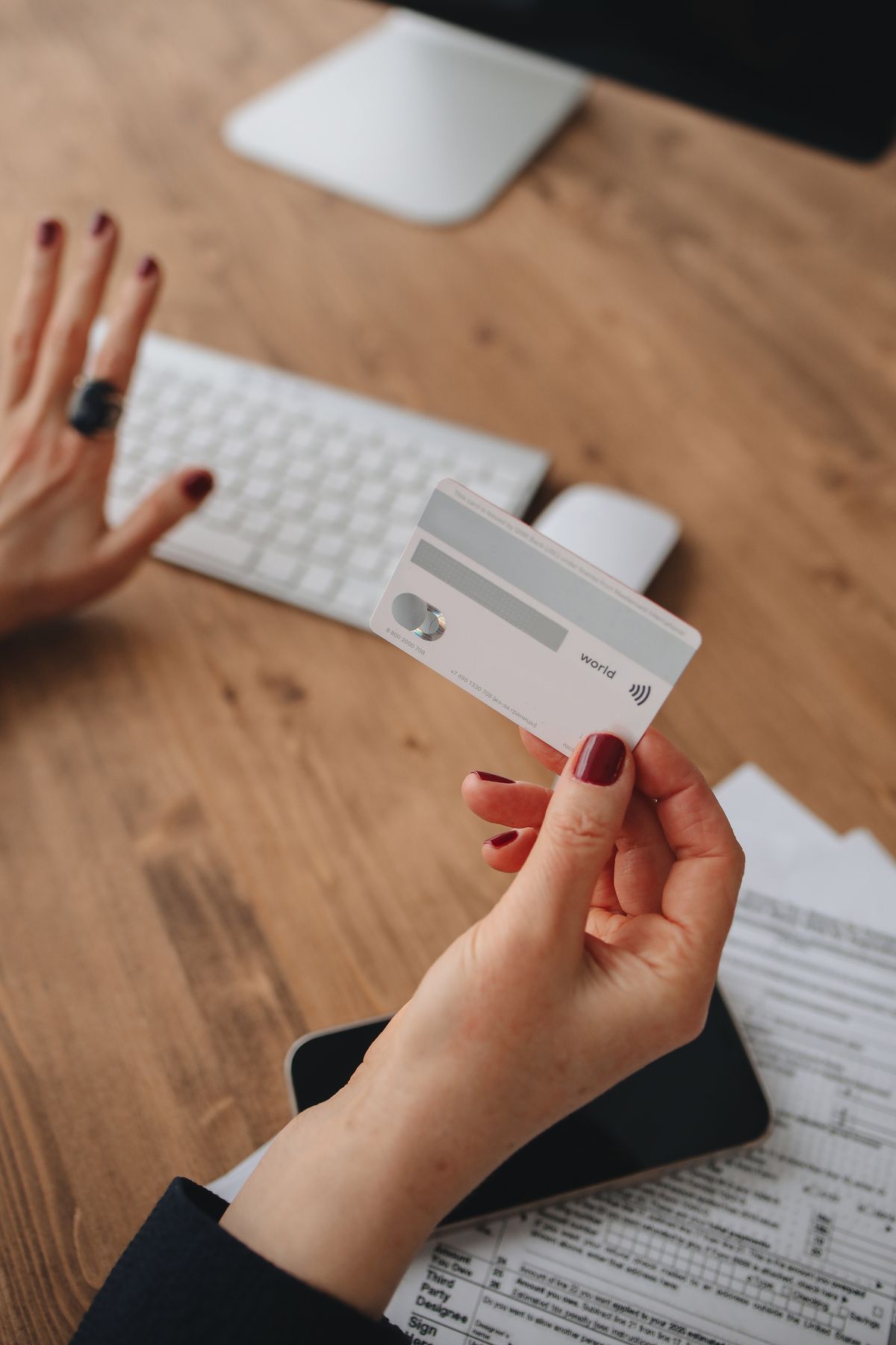 Person holding a credit card near a computer keyboard