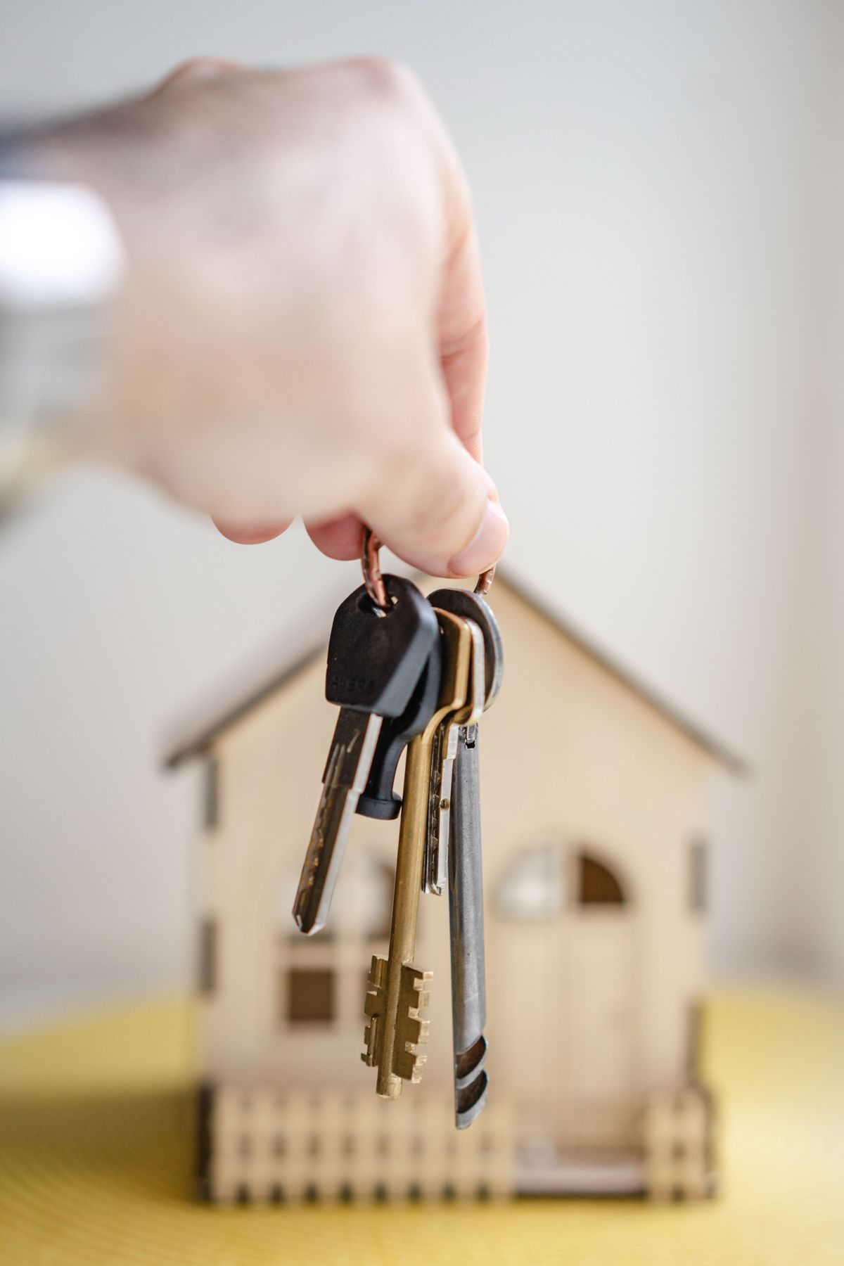 Person holding house keys beside a model home