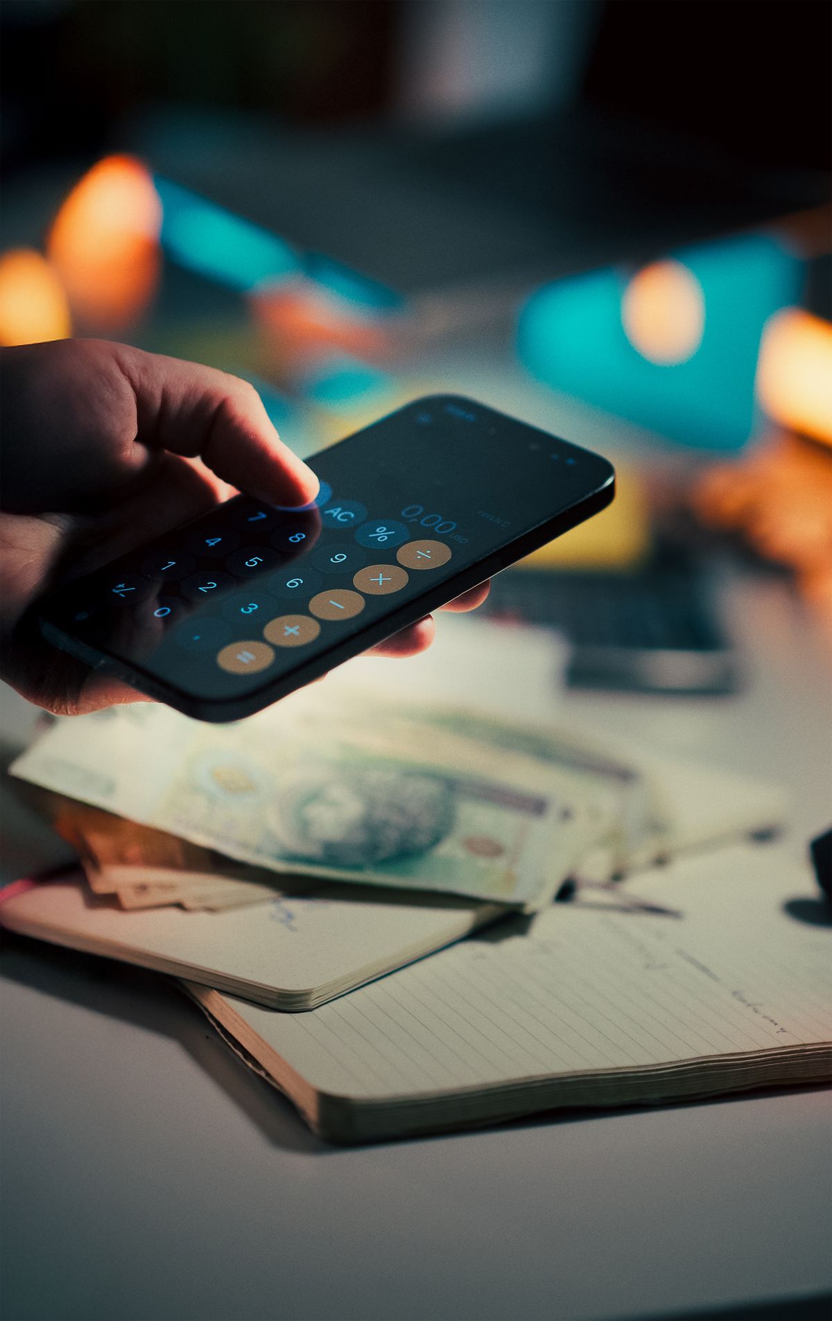 Smartphone calculator beside cash and a notebook